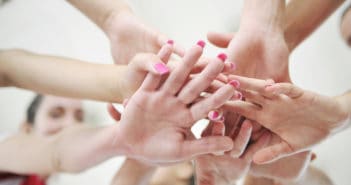 Team placing all their hands in the middle of a huddle